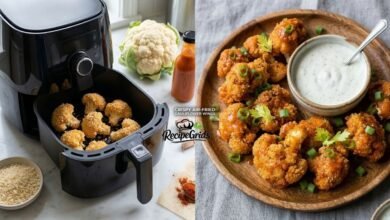 Crispy vegan air-fried cauliflower wings tossed in buffalo sauce on a wooden plate with ranch dip, next to an air fryer cooking fresh cauliflower florets. A healthy appetizer recipe by RecipeGrids.