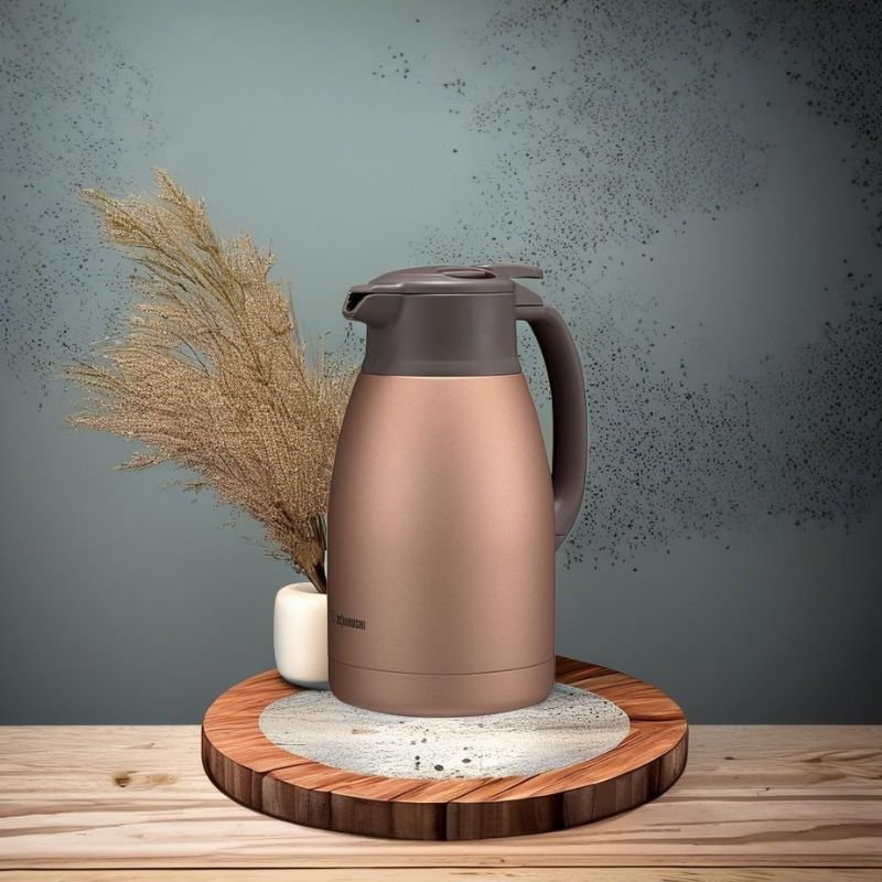 A smaller Zojirushi vacuum insulated carafe standing on a plinth, supported by an instructional visual to clarify proper maintenance like how to clean a stainless steel coffee carafe.
