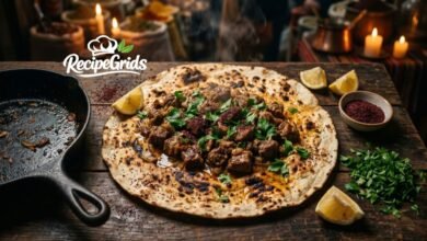 Authentic Turkish Cevurı sautéed meat served on a large charred lavaş flatbread, garnished with fresh parsley, sumac, and lemon wedges on a rustic wooden table.