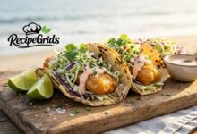 Crispy Baja-style fish tacos with fresh homemade coleslaw and chipotle crema on a wooden board, presented by RecipeGrids.