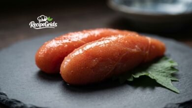 Close-up of fresh, spicy Mentaiko (Japanese pollock roe) resting on a shiso leaf over a dark slate plate, by RecipeGrids.