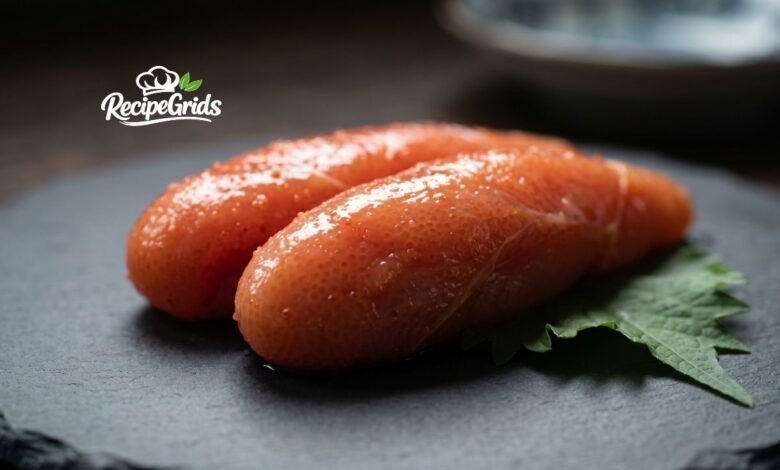 Close-up of fresh, spicy Mentaiko (Japanese pollock roe) resting on a shiso leaf over a dark slate plate, by RecipeGrids.