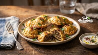 Close-up of freshly baked golden Levapioli on a rustic plate, with one piece broken open to reveal the juicy seasoned minced meat filling and steam rising.